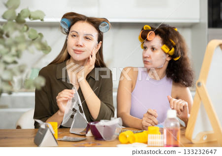Two women testing out hydrating face paper mask at home 133232647
