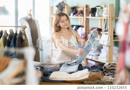 Young woman choosing jeans in clothing store Young woman choosing jeans in clothing store 133232655
