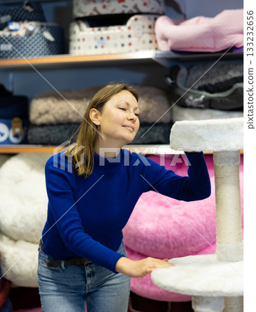 Woman choosing cat scratching post with fur platforms for cat 133232656