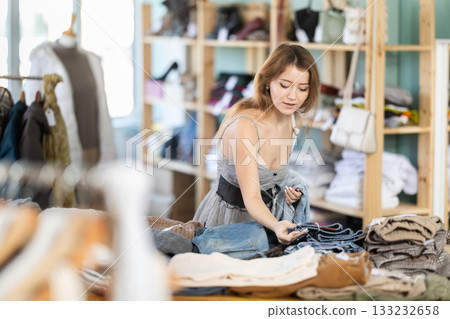 Positive young girl choosing jeans pantaloons in clothing store Positive young girl choosing jeans pantaloons in clothing store 133232658