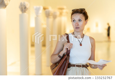 Woman looking at antique museum exhibit with brochure 133232767