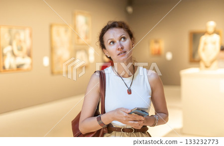 Woman with phone looking at art gallery 133232773