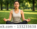 Woman meditating and relaxing on the grass in the park 133233638
