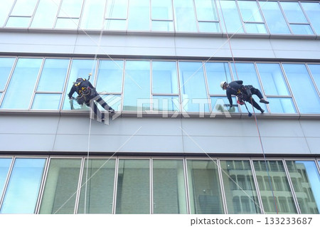 Workers cleaning windows in a high-rise building Workers cleaning windows in a high-rise building 133233687