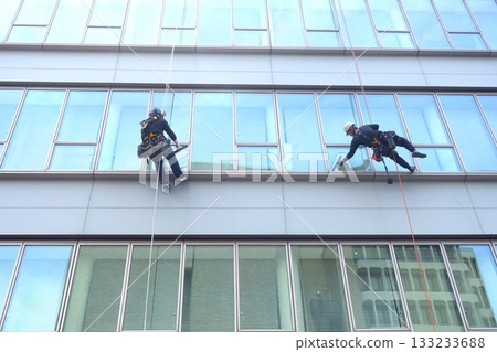 Workers cleaning windows in a high-rise building 133233688