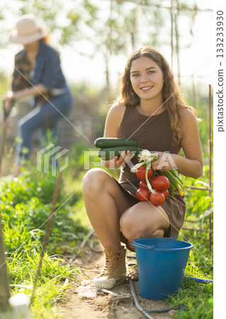 Young woman with vegetable harvest in cottage garden Young woman with vegetable harvest in cottage garden 133233930