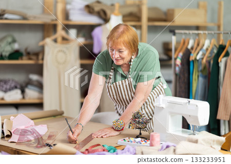 Woman dressmaker drawing pattern on paper in workshop Woman dressmaker drawing pattern on paper in workshop 133233951