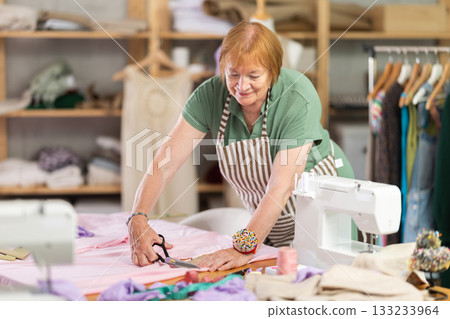 Woman seamstress cutting fabric in sewing workshop Woman seamstress cutting fabric in sewing workshop 133233964