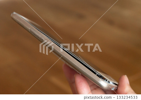 Man holding smartphone with swollen mobile battery 133234533