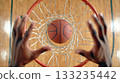 A basketball and hand viewed from directly above the hoop 133235442