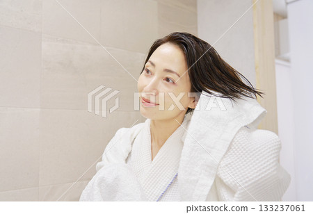 一位女士洗完澡後用浴巾擦濕頭髮。 133237061