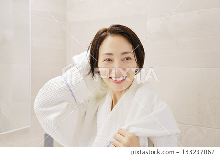 A woman wiping her wet hair with a bath towel after taking a bath 133237062