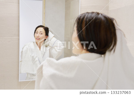 A woman wiping her wet hair with a bath towel after taking a bath A woman wiping her wet hair with a bath towel after taking a bath 133237063