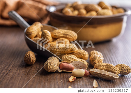 Peanuts in shell. Groundnuts  in scoop on wooden table. 133239217