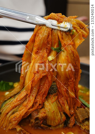 Tongs Lifting Spicy Korean Aged Kimchi from a Hot Pot 133240014