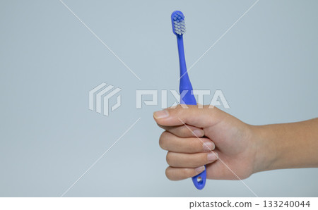 Close-up of a hand holding a blue toothbrush 133240044