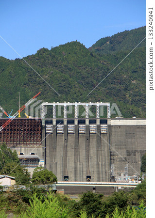 A scene of dam construction underway against the backdrop of a clear, blue autumn sky 133240941