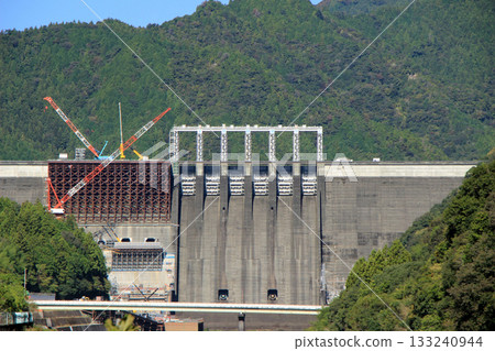 A scene of dam construction underway against the backdrop of a clear, blue autumn sky 133240944