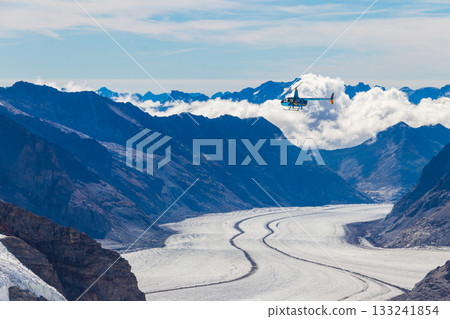 Helicopter flying over the snowy Swiss Alps in Switzerland Helicopter flying over the snowy Swiss Alps in Switzerland 133241854