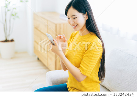 觀看在沙發的一位小姐一個智能手機 133242454