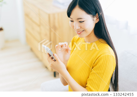 A young lady watching a smartphone on a sofa 133242455