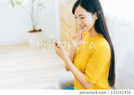 A young lady watching a smartphone on a sofa 133242456