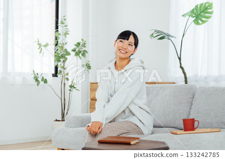 A woman relaxing in her room and thinking about exciting plans A woman relaxing in her room and thinking about exciting plans 133242785