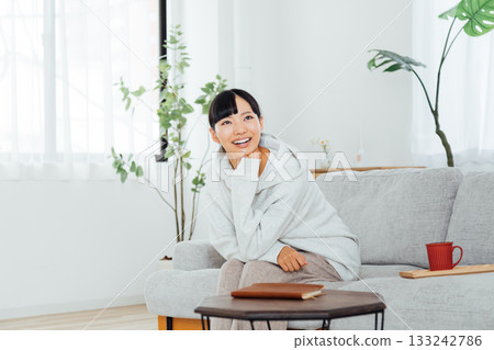A woman relaxing in her room and thinking about exciting plans A woman relaxing in her room and thinking about exciting plans 133242786