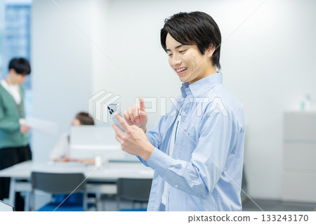 A businessman who uses a smartphone in the office A businessman who uses a smartphone in the office 133243170