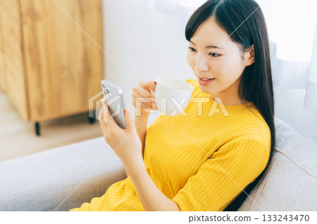 觀看在沙發的一位小姐一個智能手機 133243470