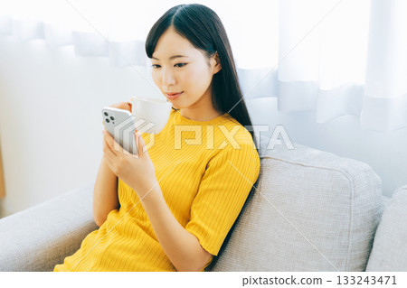 觀看在沙發的一位小姐一個智能手機 133243471