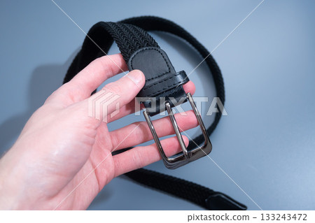 Hand Holding Black Leather Belt by Buckle Hand Holding Black Leather Belt by Buckle 133243472