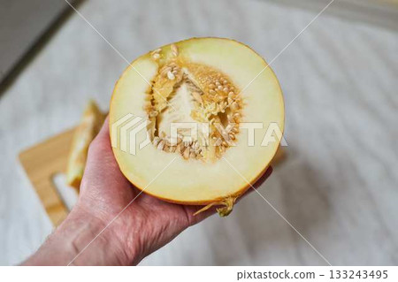 Hand-Cutting Ripe Melon on Wooden Cutting Board Hand-Cutting Ripe Melon on Wooden Cutting Board 133243495