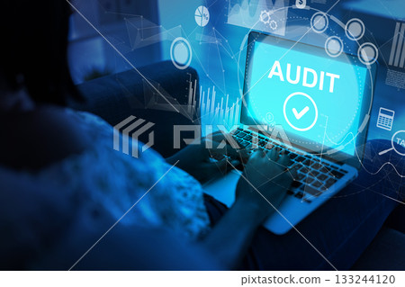 Person conducting a digital audit on a laptop in a darkened environment at night 133244120