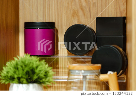 Colorful jars and containers arranged neatly on a wooden shelf in a cozy setting 133244152