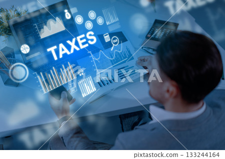 Man analyzing tax data on a laptop in a modern office setting during the day 133244164