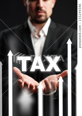 Businessman holds tax symbol, highlighting financial growth and fiscal responsibility in an office 133244346