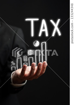 Businessman illustrating tax growth through a glowing graph in a dark setting 133244348