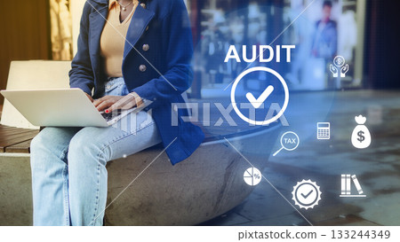 Working on audit tasks with a laptop in a modern urban setting during the day 133244349