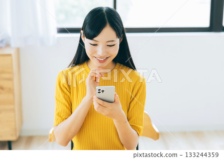 年輕女子在客廳看智慧型手機 133244359