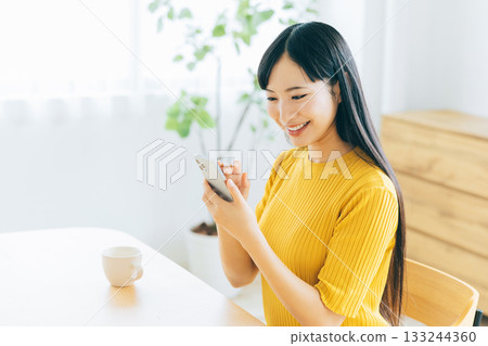 年輕女子在客廳看智慧型手機 133244360