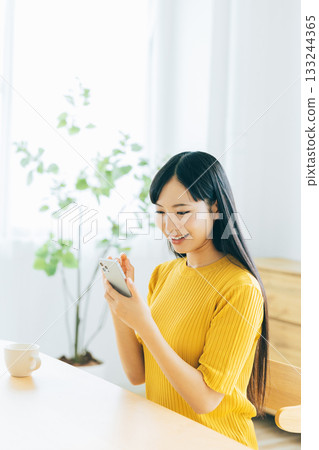 Young woman looking at her smartphone in the living room 133244365
