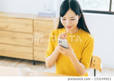 年輕女子在客廳看智慧型手機 133244921