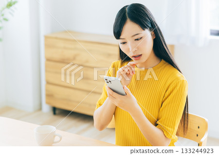 A young woman worried while looking at her smartphone A young woman worried while looking at her smartphone 133244923