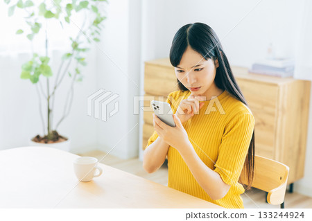 A young woman worried while looking at her smartphone A young woman worried while looking at her smartphone 133244924