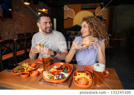 Couple enjoying burgers and beer at a restaurant 133245300