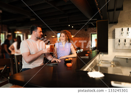 Couple drinking beer at the counter in a brewery Couple drinking beer at the counter in a brewery 133245301
