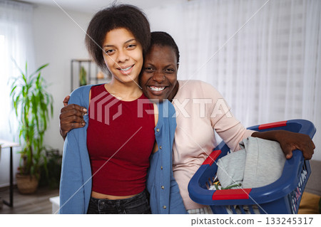 Two happy black women embracing and holding laundry basket 133245317