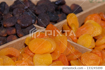 Dried fruit selection displays vibrant colors and rich textures of sweet apricots and dark prunes at a bustling market stand Dried fruit selection displays vibrant colors and rich textures of sweet apricots and dark prunes at a bustling market stand 133245899