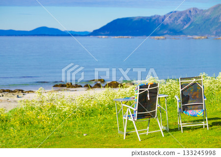 Camping portable chairs and table on fjord shore Camping portable chairs and table on fjord shore 133245998